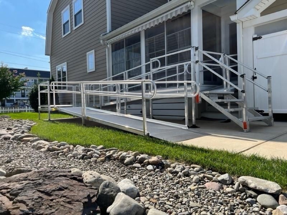 Modular aluminum wheelchair ramp with handrails along a residential walkway